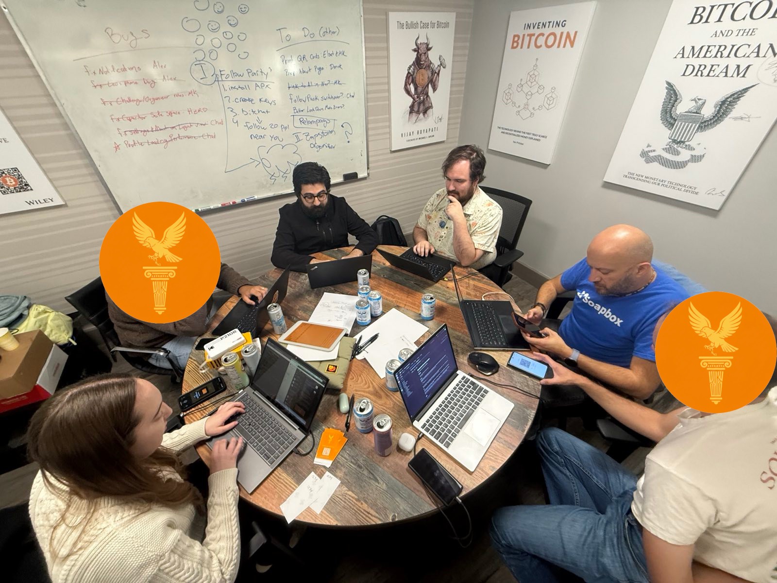 The full Pathos team working around a conference table with laptops, whiteboards covered in ideas behind them
